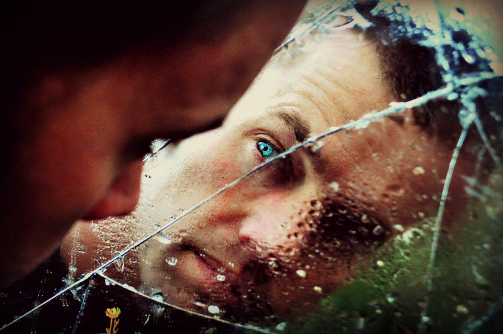 Man looking into broken mirror